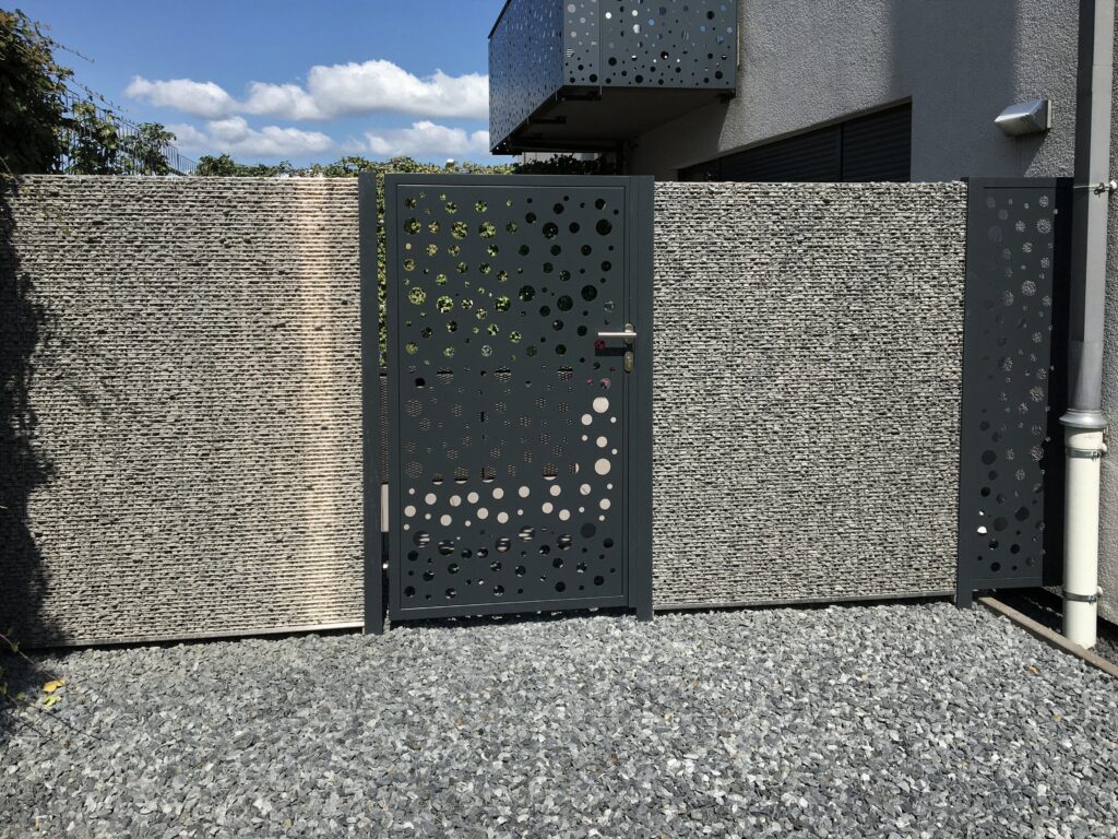Moderne, maßgefertigte Gartentür aus Stahl mit laser­geschnittenem Design-Muster als Sichtschutz, realisiert von metallic DESIGN Sàrl – hochwertiger Metallbau aus Luxemburg für exklusive Außenanlagen