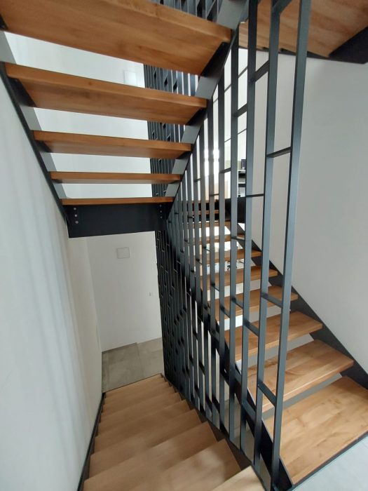 Design-Innentreppe aus Stahl mit Holzstufen und vertikalem Metallgeländer – hochwertiger Metallbau von metallic DESIGN Sàrl, Luxemburg.