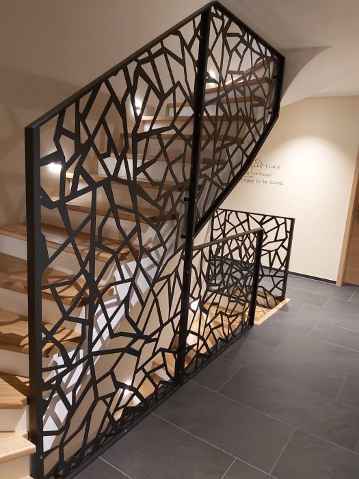 Design-Treppengeländer aus Stahl mit gelasertem Muster, pulverbeschichtet in Schwarz, kombiniert mit Holzstufen – maßgefertigt von metallic DESIGN Sàrl in Luxemburg