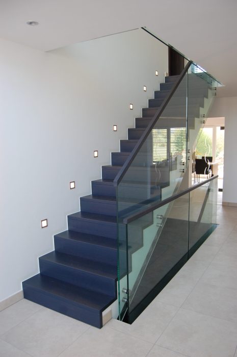 Ganzglasgeländer an einer schwarzen Innentreppe mit einem schwarzen Holzhandlauf und mit Punkthaltern aus Edelstahl, maßgefertigt von metallic DESIGN Sàrl in Luxembourg